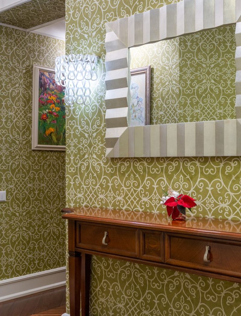 Elegant hallway finished in green botanical damask wallpaper with a console table and mirror
