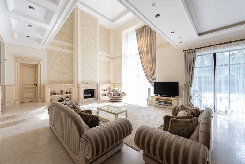 Sophisticated cream living room with patterned wall covering, twin sofas and a fireplace
