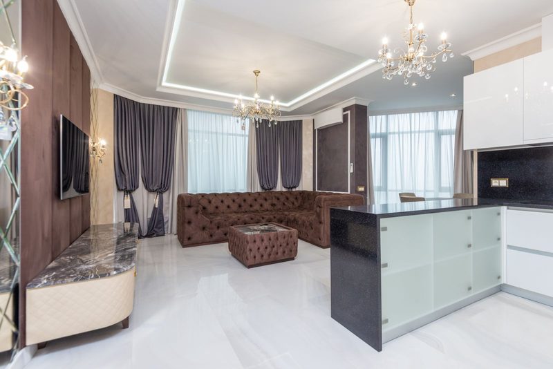 Open-plan living space with warm brown drapery, a tufted bench and marble detailing